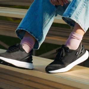 WATH256 -Lifestyle Woman wearing Kizik Women's Athens 2 in Black and White sitting on bleachers.