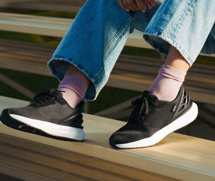 WATH256 -Lifestyle Woman wearing Kizik Women's Athens 2 in Black and White sitting on bleachers.