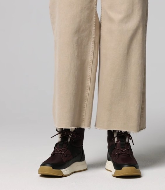 Woman Wearing Sorel Whitney III Mid WP in Red Lodge/Black with Tan Pants